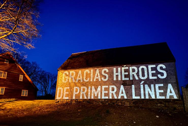 Wall with a digital projection that reads, "Gracias Heroes de Primera Linea"