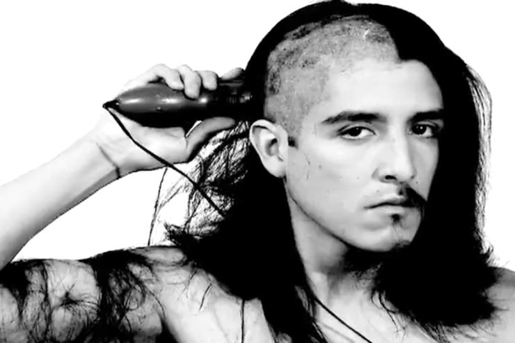 Black and white photo of Emilio Rojas; a man is shaving head and half of his goatee is shaved
