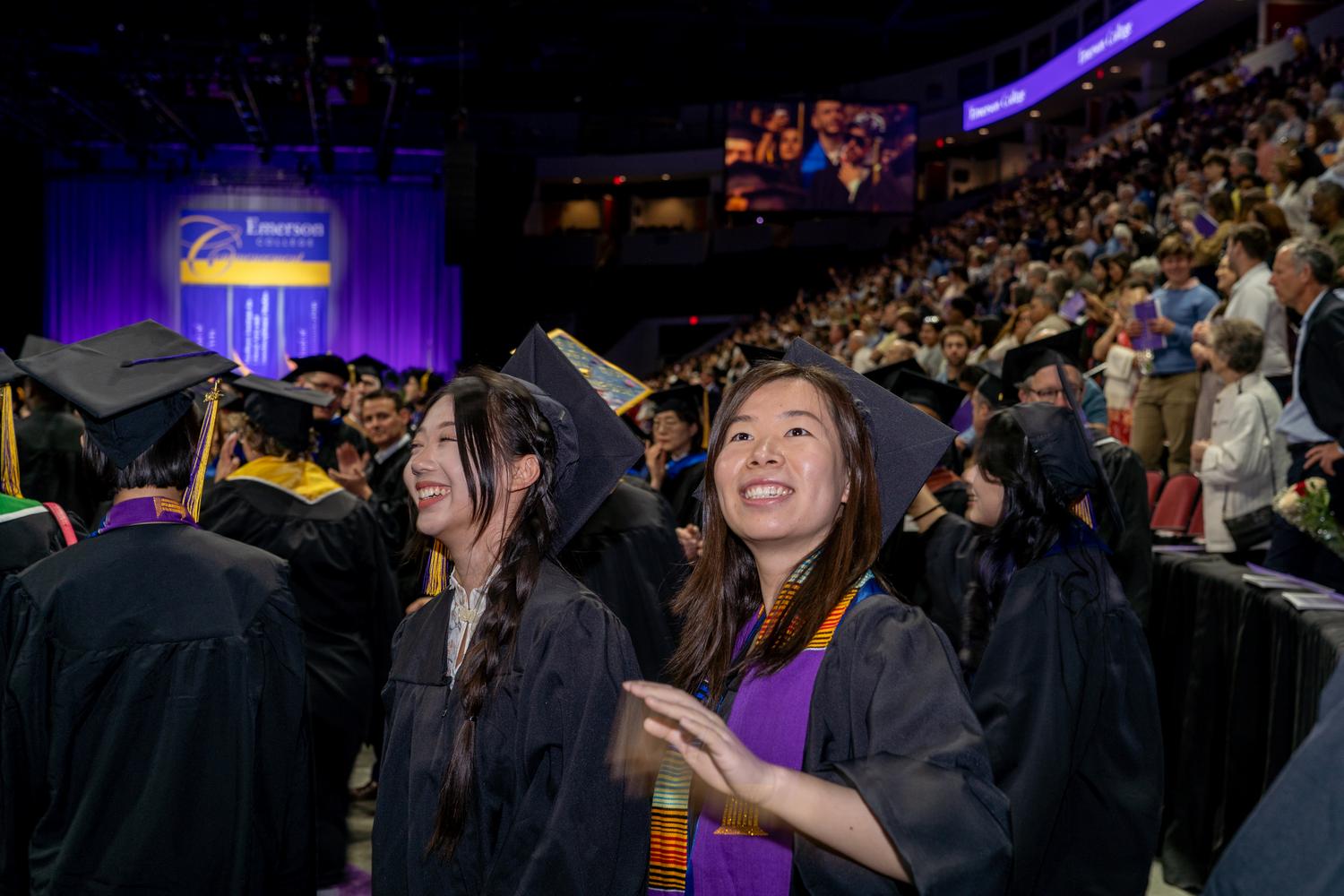 Students smiling at commencement while wearing regalia