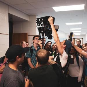 Danny Madden on set with camera surrounded by actors