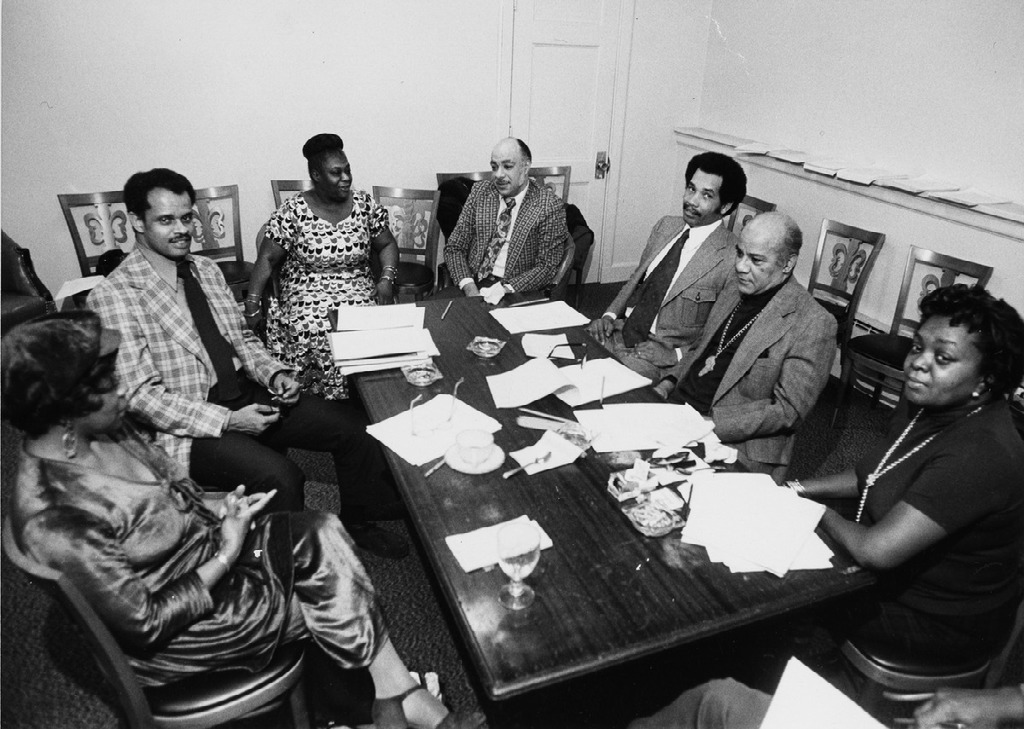Elma Lewis sitting in a meeting room with a group of adults