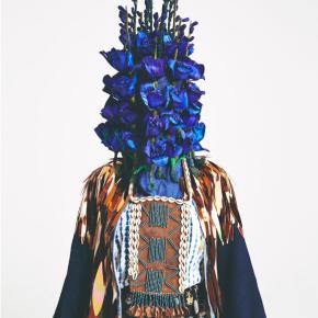 Laura Anderson Barbata's 'Queen' piece, a masked figure with an indigo flower head, fringe shirt and beaded accents