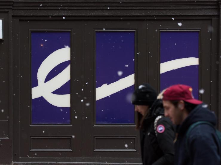 Two students walking in front of the Emerson College flourish outdoors, while it's snowing