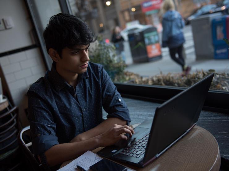 Student working on laptop in a cafe