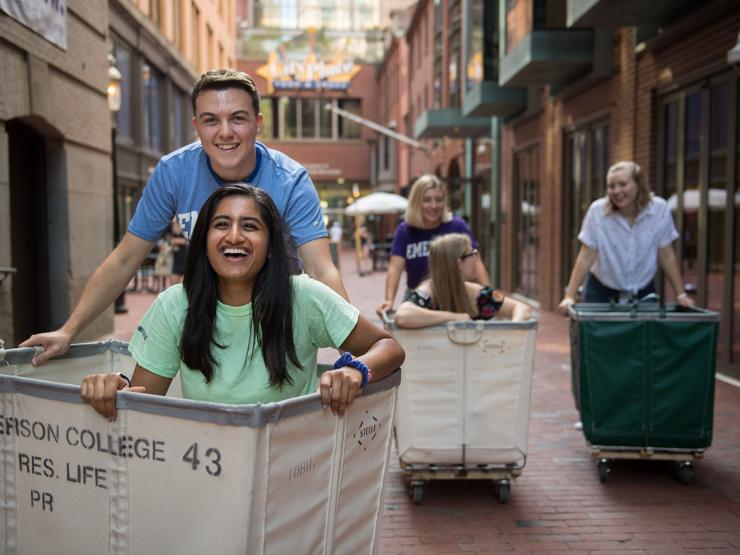 Two students riding in a move-in cart down the ally