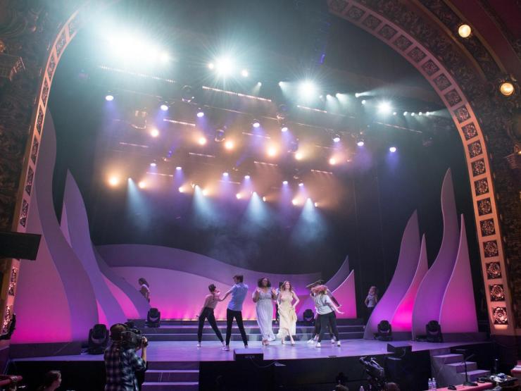 Students performing on a brightly lit stage with purple uplighting for the EVVY Awards