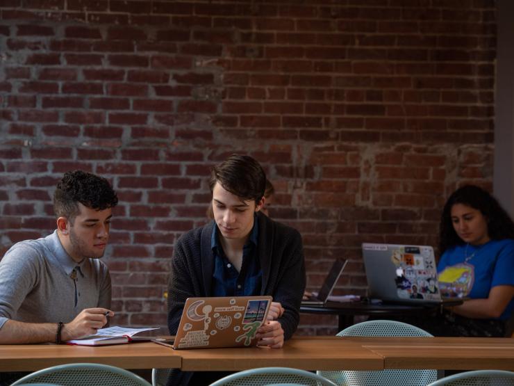 Students sitting on table with laptops in the Lion's Den