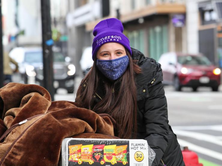 Student in purple Emerson beanie and winter jacket, pushing cart full of personal belongings