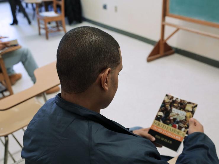 An EPI student holds a classroom text at MCI Concord (Photo courtesy of MA DOC)