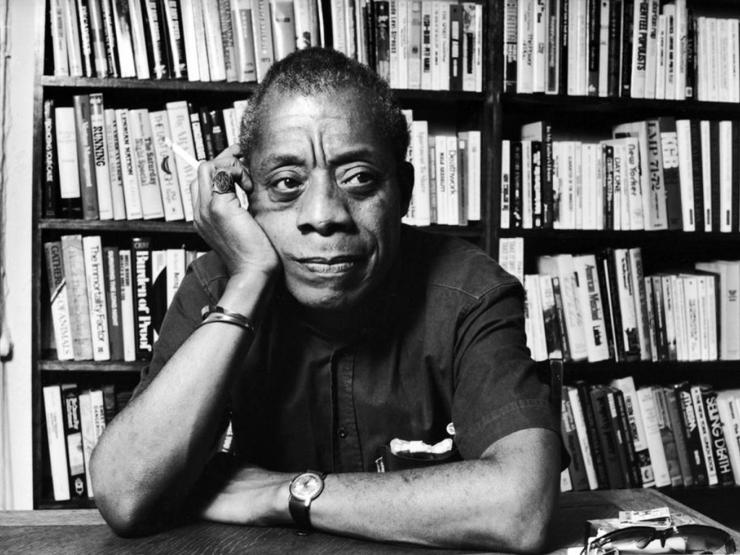 Black and white photo of James Baldwin sitting at desk (New Yorker Magazine, 2014)