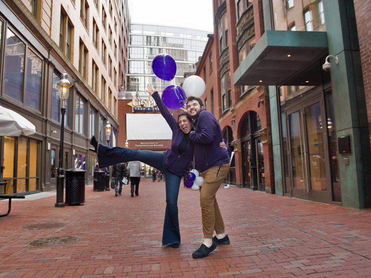 Two students holding purple and white balloons in the Bolyston Place Alley