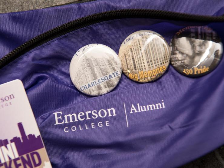 3 circular pins with city imagery on a purple fabric that has the Emerson College name, logo and alumni names shown