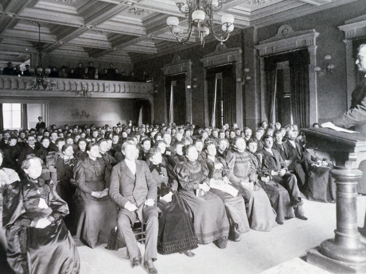 Black and white photo of an audience watching a show on a stage