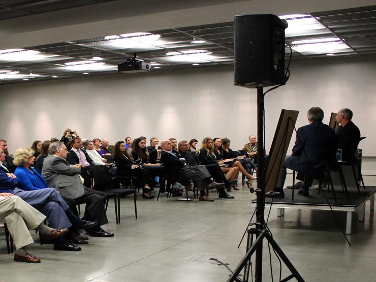 Two men presenting on stage to an audience of adults
