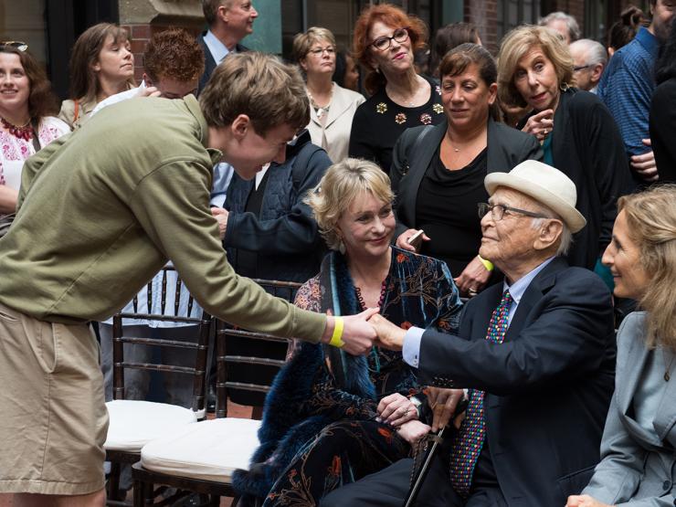 Student reaches down to shake Norman Lear’s hand in a crowd of alumni on Norman Lear Day