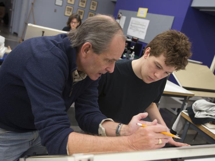Professor and student working together and leaning over a desk