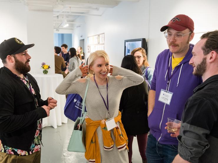 group of graduate students standing and talking at gallery event