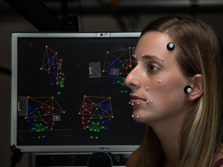 woman in FACE Lab with sensors sits in front of computer screen