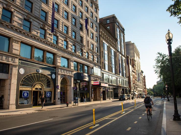 A cyclist pedaling down Boylston Street across from Emerson College buildings