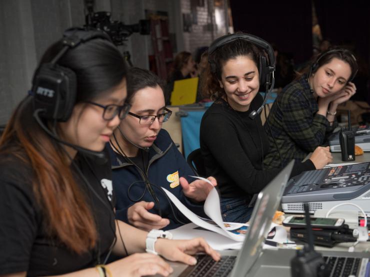 Students wearing headsets at computers, doing media production work