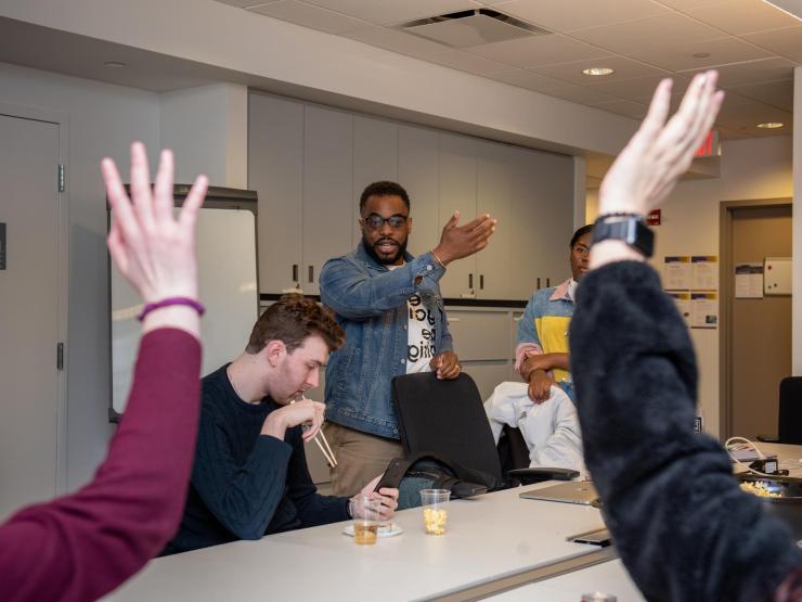 Emerson faculty in a meeting with some hands raised