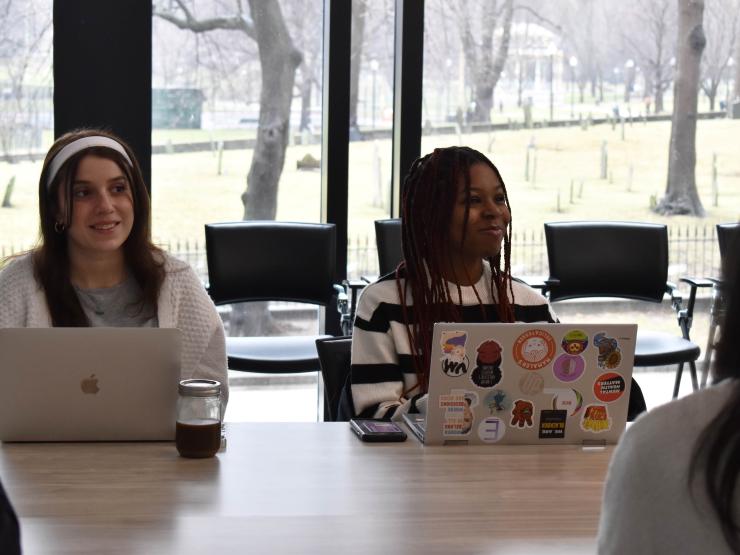 Two students sitting at a table with laptops