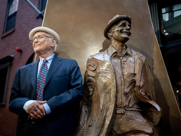 The late Normal Lear as an elderly man stands next to the Emerson statue of his younger self