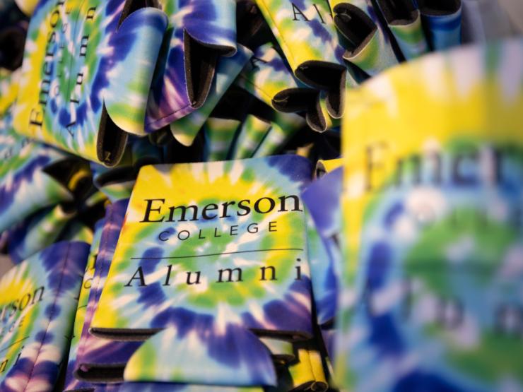 A collection of tie-dye colored beverage cozies labeled "Emerson Alumni"