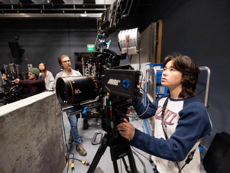 A student handling camera equipment in a studio