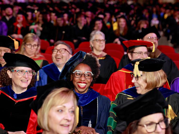 Faculty members in their regalia smiling during Commencement
