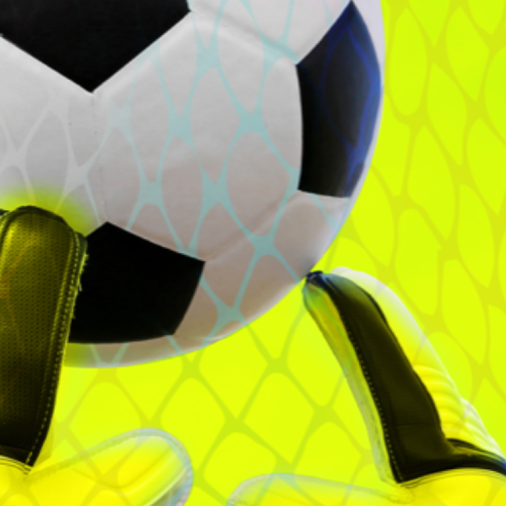 A closeup of a soccer ball approaching a goalie's gloves against a yellow background