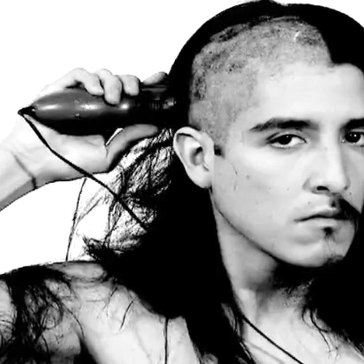 Black and white photo of Emilio Rojas; a man is shaving head and half of his goatee is shaved