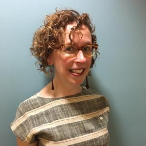 Picture of Jaqi Holland, assistant director of academic support at the WARC. Curly hair and glasses.