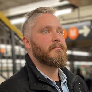 Semi-profile image of Alex Svensson in NYC subway underground, looking pensive.
