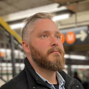 Semi-profile image of Alex Svensson in NYC subway underground, looking pensive.