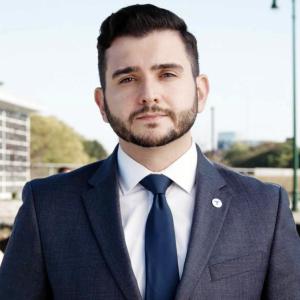 Andrew Cassidy wearing a blue suit, white shirt, and blue tie.