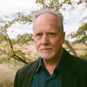 Author Daniel Tobin stands against a backdrop of foliage and greenery