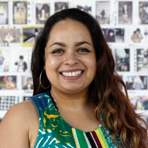 Smiling picture of Alejandra Spruill with polaroid wall in the back. 