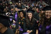 A large crowd of students smiling at Commencement, wearing regalia