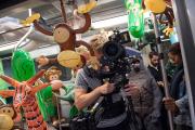 Students ride the MBTA while carrying film equipment and props