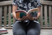 A student reads on a park bench