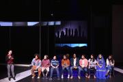 a group of students sitting in a row on stage next to a speaker