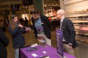 Two people standing at a display table with Emerson College-branded signage