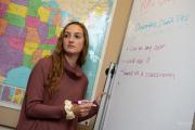 Student writing on a white board and looking at peers for opinions