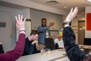 Image of people around table raising their hands