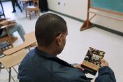 An EPI student holds a classroom text at MCI Concord (Photo courtesy of MA DOC)