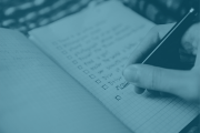Photo of someone writing in a notebook with blue filter over image