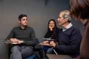 A professor lectures from a chair while 2 students watch him