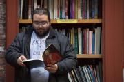 A student reading a book in front of a book shelf