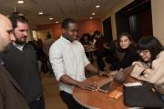 A group of graduate students stand around a table and look at a computer